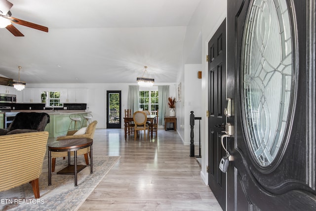 foyer with light wood-type flooring, ceiling fan with notable chandelier, and sink