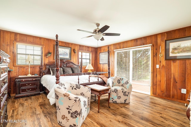 bedroom with wooden walls, wood finished floors, and a ceiling fan