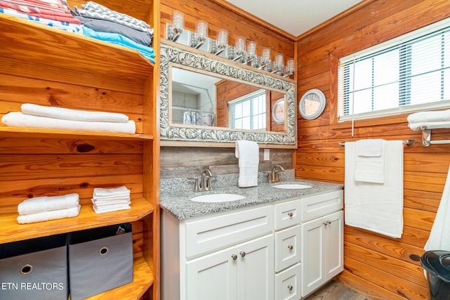 bathroom featuring double vanity, tasteful backsplash, wood walls, and a sink