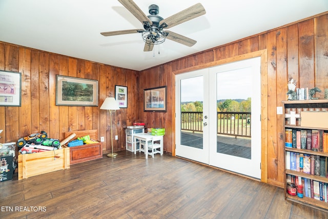 interior space with wood walls, ceiling fan, french doors, and dark hardwood / wood-style floors