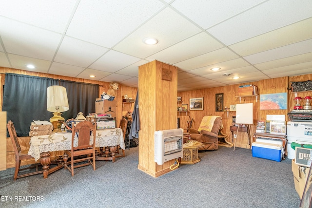 carpeted living area featuring recessed lighting, a drop ceiling, heating unit, and wood walls