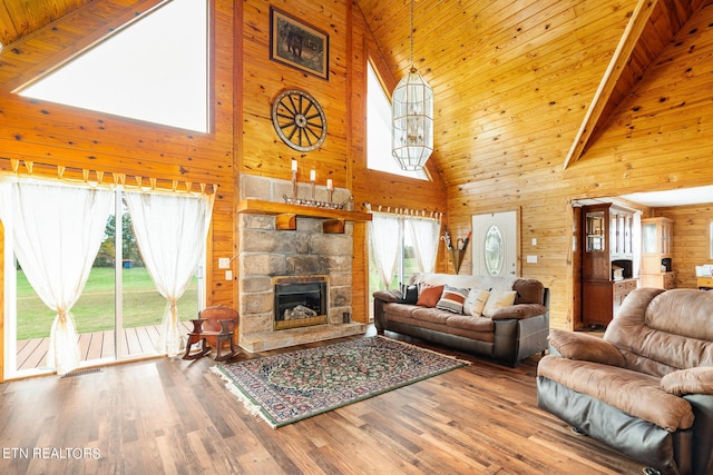 living room with high vaulted ceiling, wood walls, a healthy amount of sunlight, and wood finished floors
