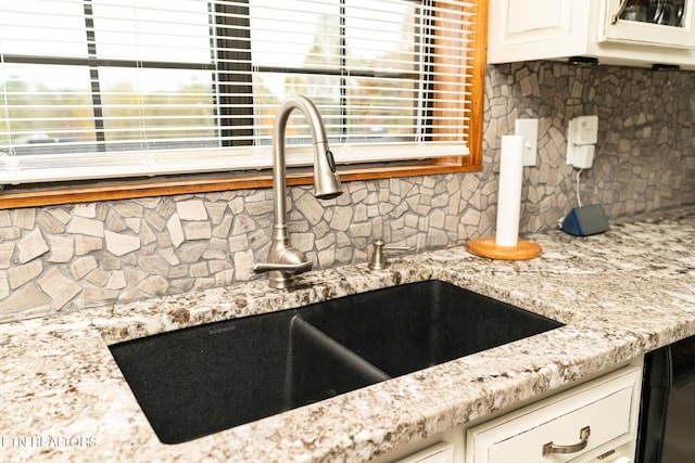 details with white cabinets, light stone counters, a sink, glass insert cabinets, and tasteful backsplash