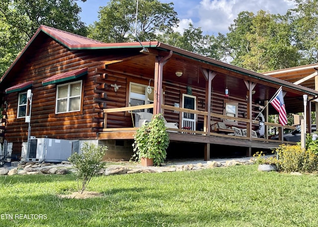 back of property featuring log siding and a lawn