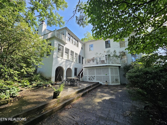 back of property with brick siding, a chimney, and a patio area