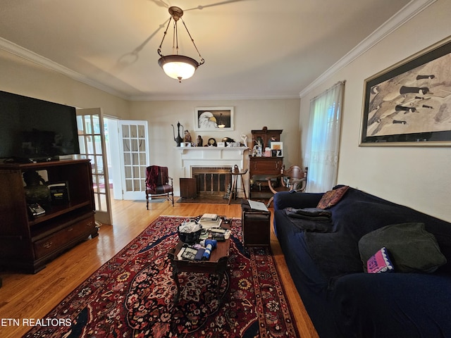 living area featuring light wood-style floors, a fireplace with flush hearth, ornamental molding, and french doors