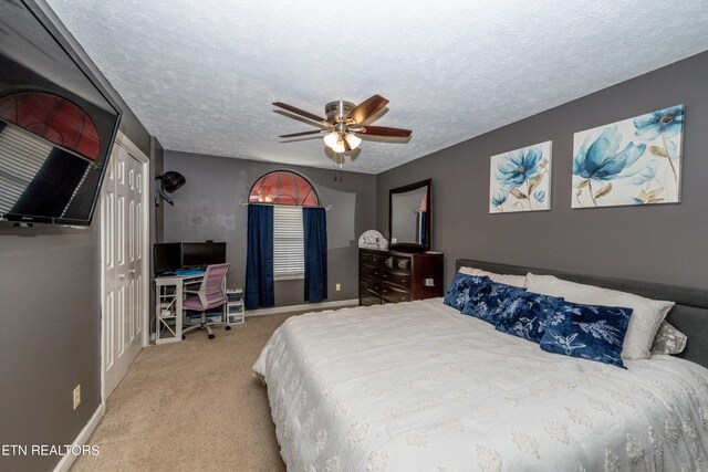 carpeted bedroom featuring ceiling fan, a textured ceiling, and a closet