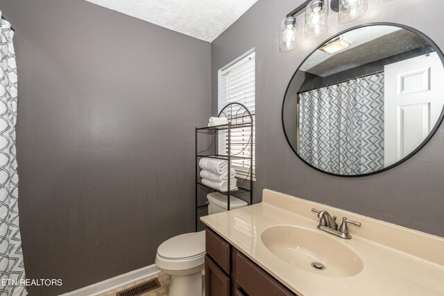 bathroom featuring vanity, a textured ceiling, toilet, and tile patterned flooring