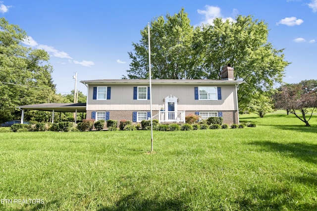 split foyer home with a carport, brick siding, a chimney, and a front yard