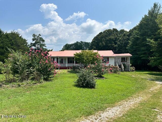 single story home featuring covered porch and a front yard