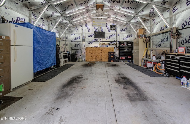 garage with white fridge and a workshop area