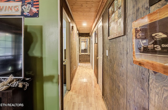 hall with wood walls, wooden ceiling, and light hardwood / wood-style flooring