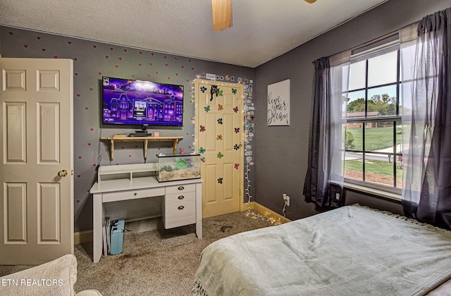 carpeted bedroom featuring multiple windows, a textured ceiling, and ceiling fan