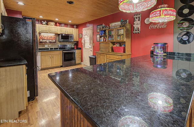 kitchen with light brown cabinets, hanging light fixtures, stainless steel appliances, dark stone counters, and light hardwood / wood-style floors