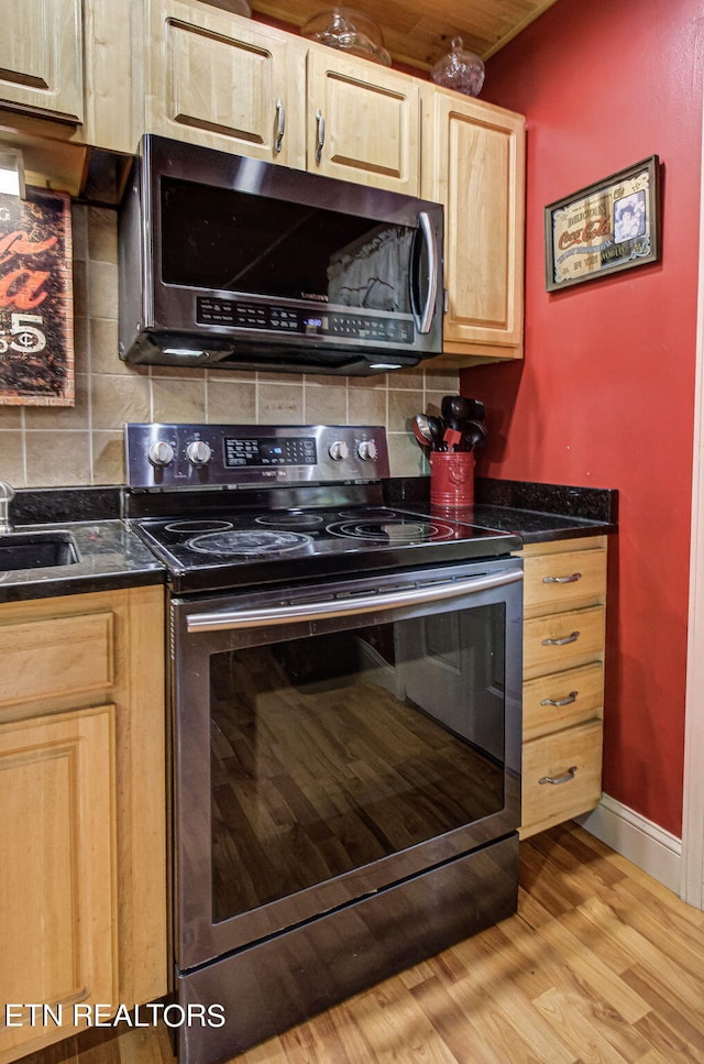 kitchen with appliances with stainless steel finishes, light hardwood / wood-style flooring, decorative backsplash, and sink