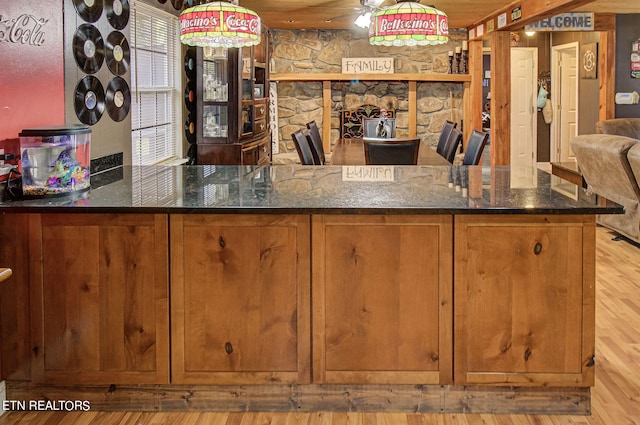 interior space featuring light hardwood / wood-style flooring, decorative light fixtures, wooden ceiling, and dark stone counters