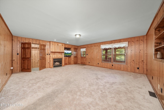 unfurnished living room with light carpet and wooden walls