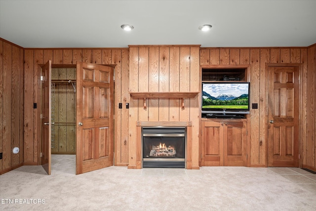 unfurnished living room with wood walls and light colored carpet