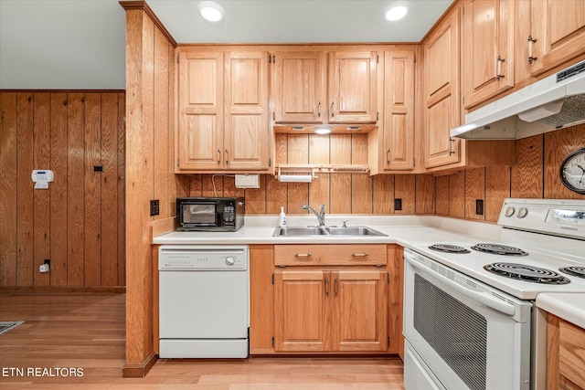 kitchen featuring white appliances, light wood-type flooring, wooden walls, and sink