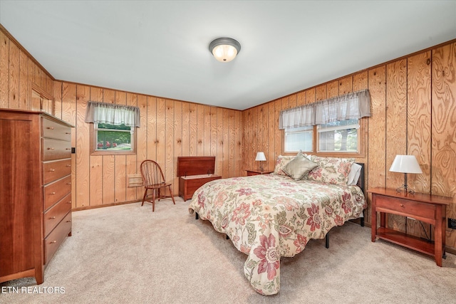 bedroom featuring wood walls and light colored carpet