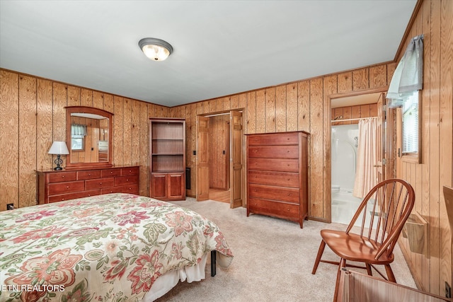 carpeted bedroom with wood walls and connected bathroom