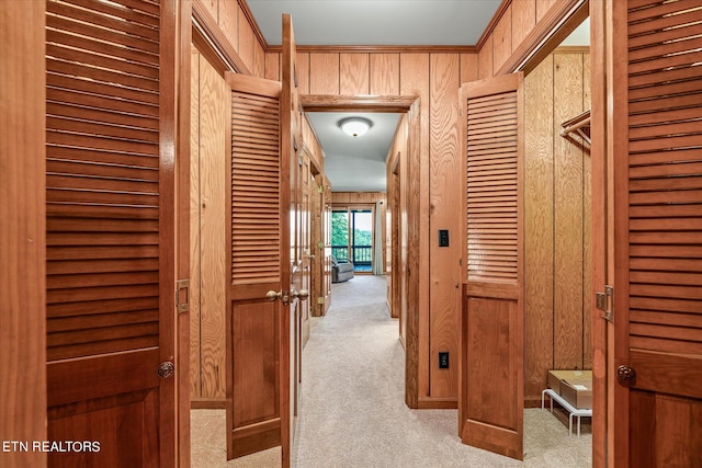 hallway featuring wood walls and light carpet