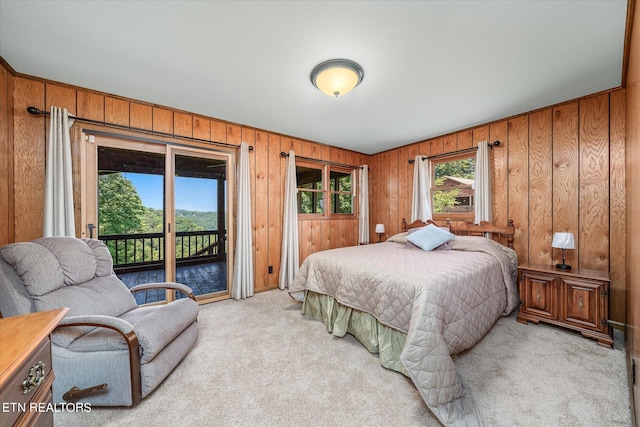 bedroom with access to exterior, wooden walls, and light colored carpet