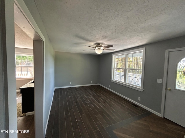 interior space featuring ceiling fan, dark hardwood / wood-style floors, a textured ceiling, and plenty of natural light