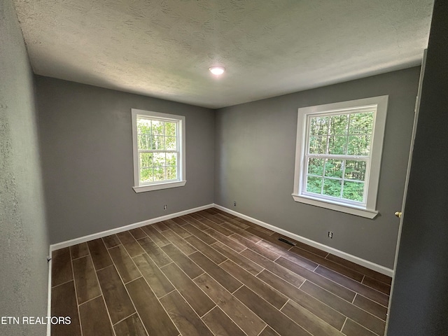 unfurnished room featuring wood-type flooring and a textured ceiling