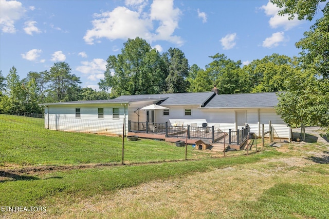 rear view of property with a deck and a yard