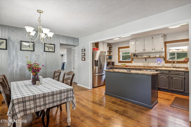 dining space featuring a chandelier, sink, wood-type flooring, and a healthy amount of sunlight