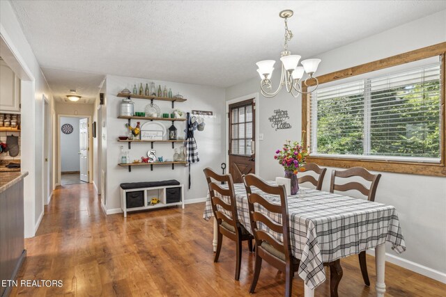 dining space with a textured ceiling, hardwood / wood-style flooring, and a chandelier