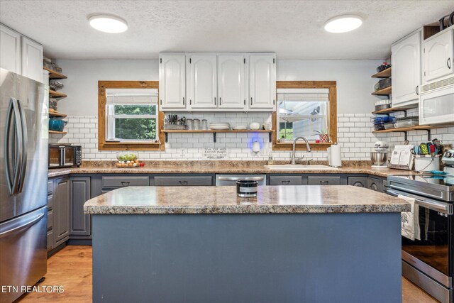 kitchen featuring tasteful backsplash, stainless steel appliances, sink, and light hardwood / wood-style floors