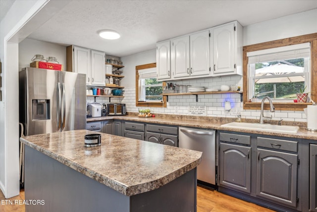 kitchen featuring light hardwood / wood-style flooring, gray cabinets, backsplash, stainless steel appliances, and sink