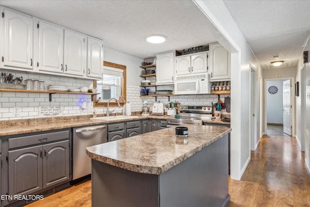 kitchen featuring decorative backsplash, a textured ceiling, hardwood / wood-style floors, appliances with stainless steel finishes, and white cabinets