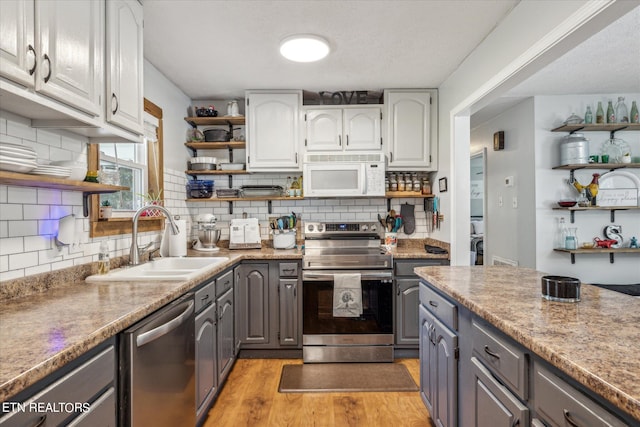 kitchen featuring appliances with stainless steel finishes, sink, light hardwood / wood-style flooring, and gray cabinets