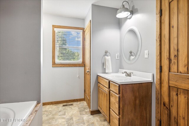 bathroom with tile patterned floors, vanity, and a tub to relax in