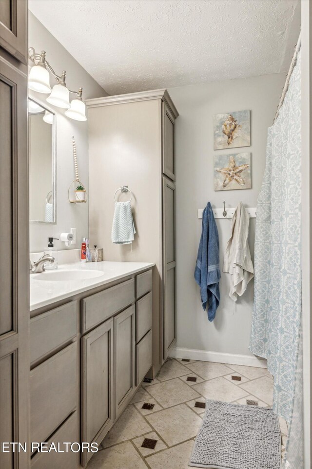 bathroom with a textured ceiling, vanity, and tile patterned flooring