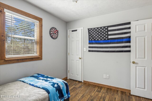 bedroom with a textured ceiling and dark wood-type flooring