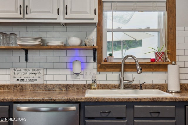 kitchen featuring decorative backsplash, white cabinets, stainless steel dishwasher, and sink