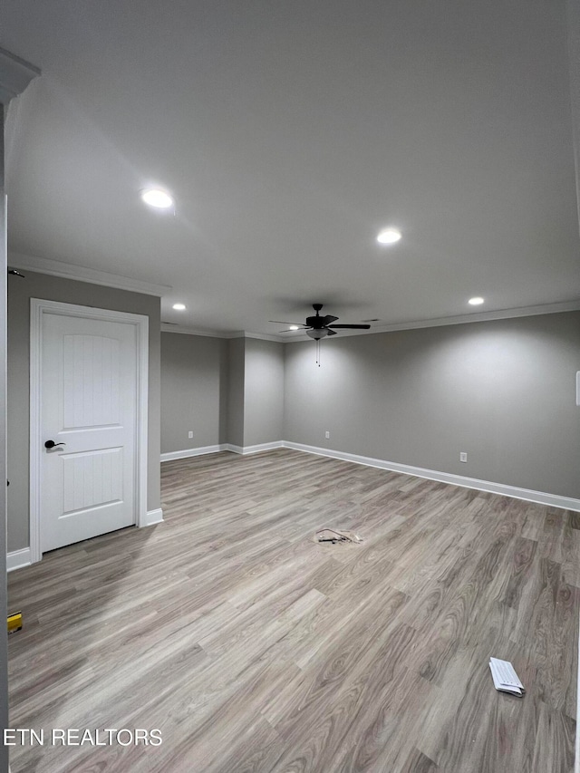 basement featuring ceiling fan, crown molding, and light hardwood / wood-style flooring