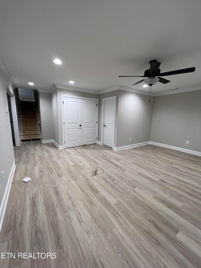 basement featuring ceiling fan, crown molding, and light hardwood / wood-style flooring