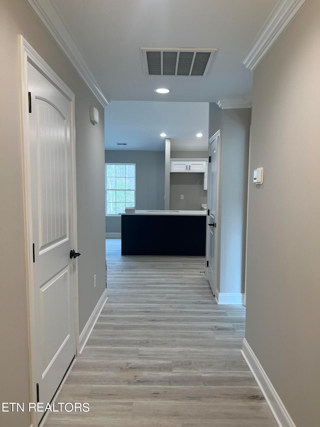 hall featuring ornamental molding and light hardwood / wood-style floors