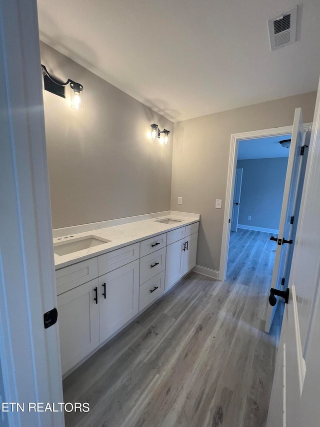 bathroom featuring dual bowl vanity and hardwood / wood-style flooring