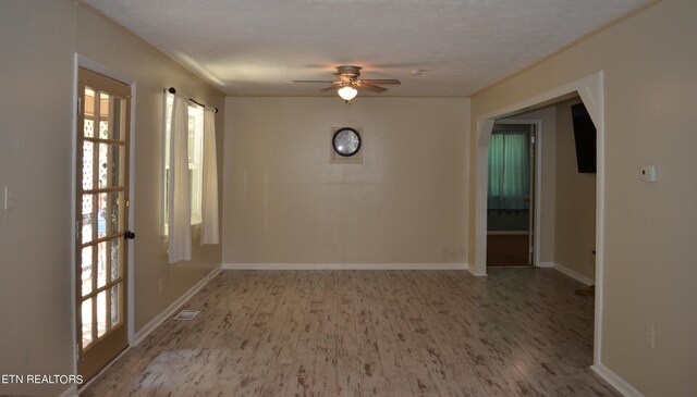 empty room with ceiling fan, wood-type flooring, and a textured ceiling