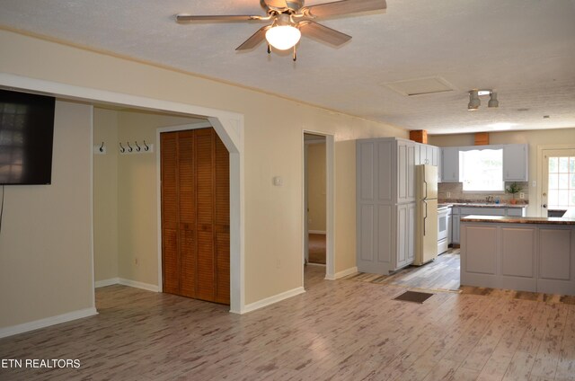 kitchen with tasteful backsplash, white appliances, white cabinetry, ceiling fan, and light hardwood / wood-style flooring