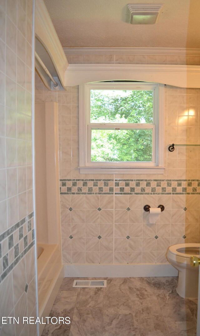 bathroom featuring tiled shower / bath, tile walls, toilet, and tile patterned flooring