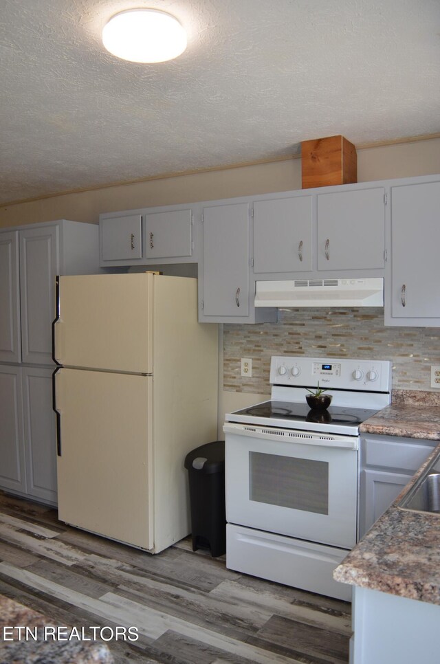 kitchen with backsplash, a textured ceiling, light wood-type flooring, and white appliances