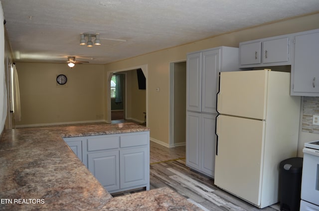 kitchen featuring light wood-type flooring, white appliances, a textured ceiling, white cabinetry, and ceiling fan