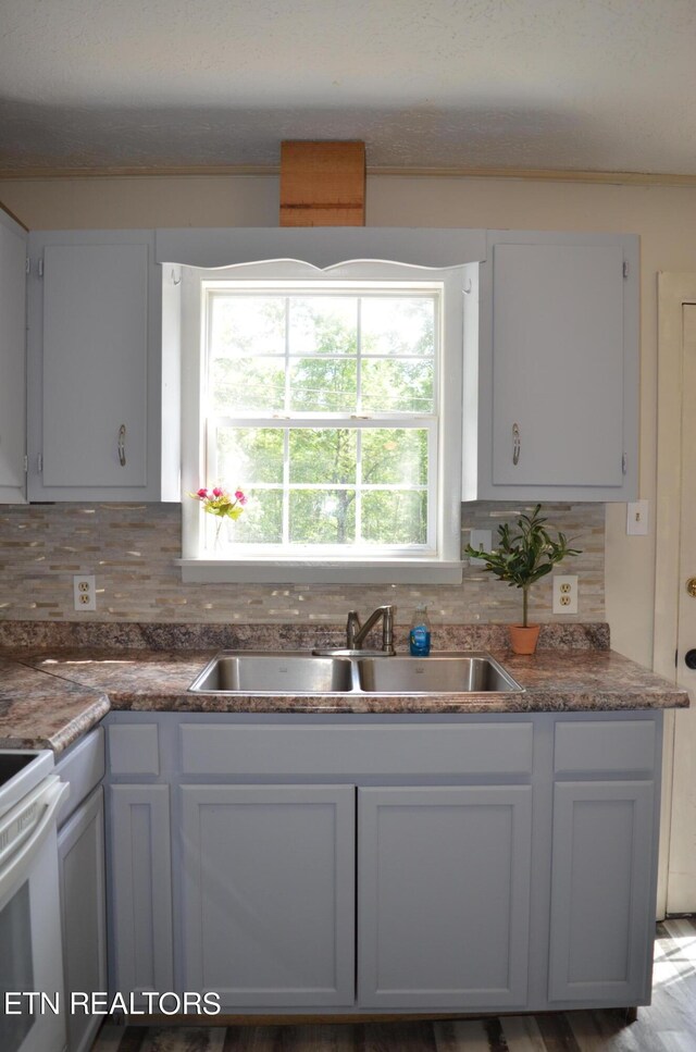 kitchen featuring backsplash, light wood-type flooring, white range oven, and sink